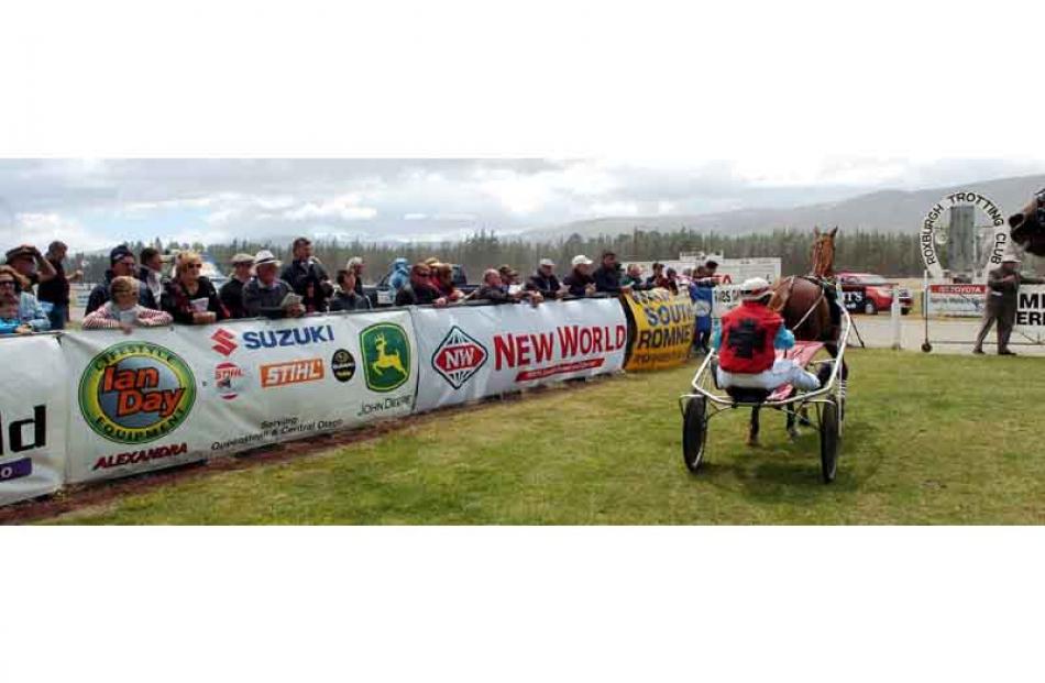 Race-goers study the horse in the birdcage at the Roxburgh Trotting Club's meeting.
