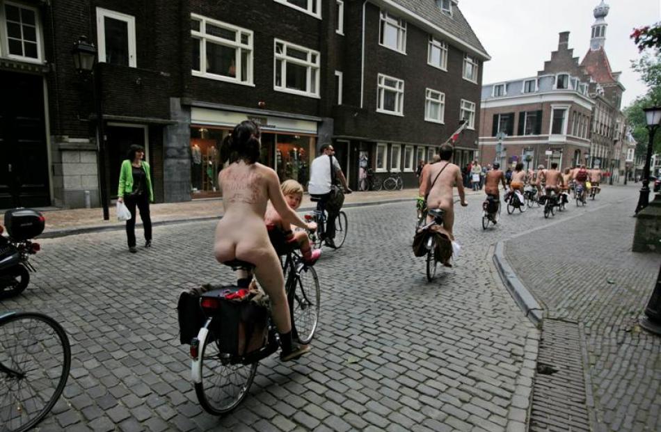 A child looks back as a woman rides with other participants through the center of Utrecht,...