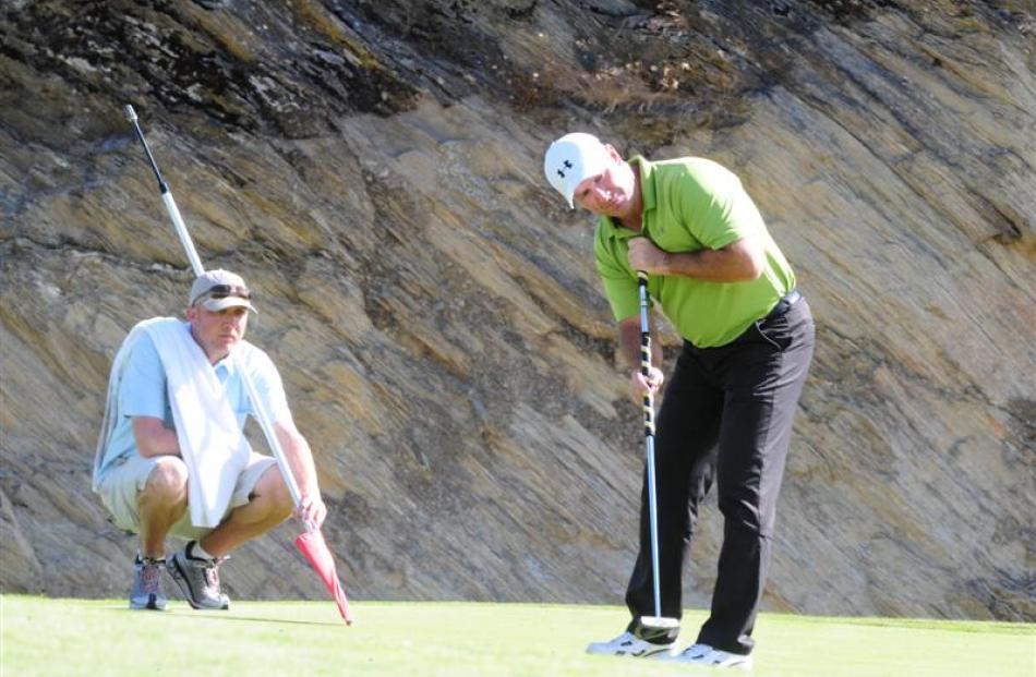 Australian Peter Lonard putts as his caddy, Bill Harke, looks on.