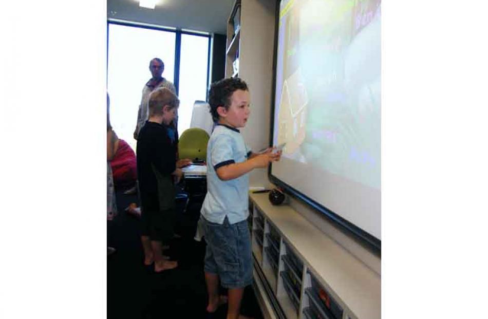 New pupil James Scoles (5), of Lakeside Estate, tries out the interactive whiteboard in `...