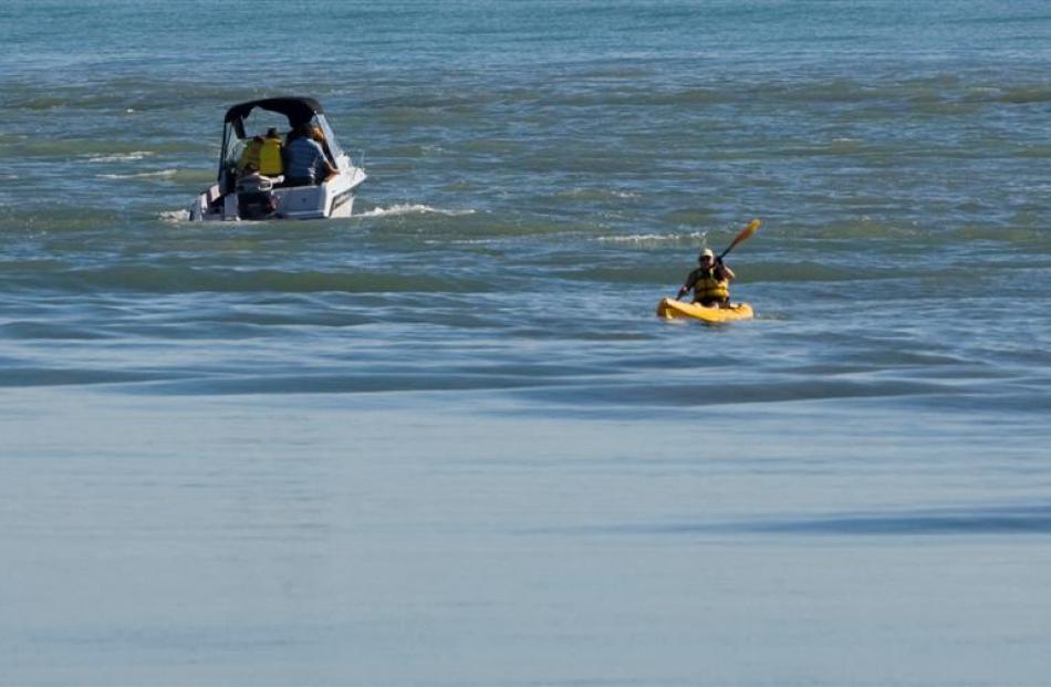 A kayak and a small boat pass through the "surge" as a tsunami warning was issued for the...