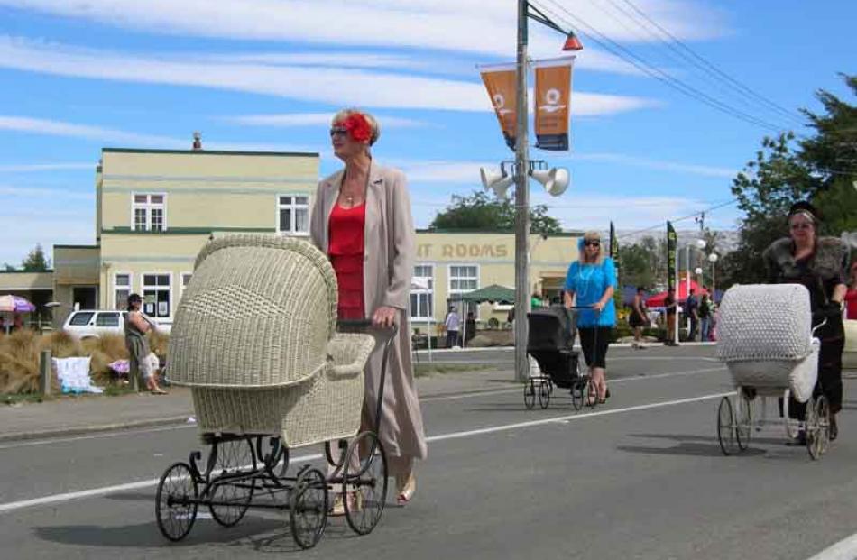 Bygone babes . . . Aptly-attired women push prams from the 1920-40s down Ranfurly's main street.