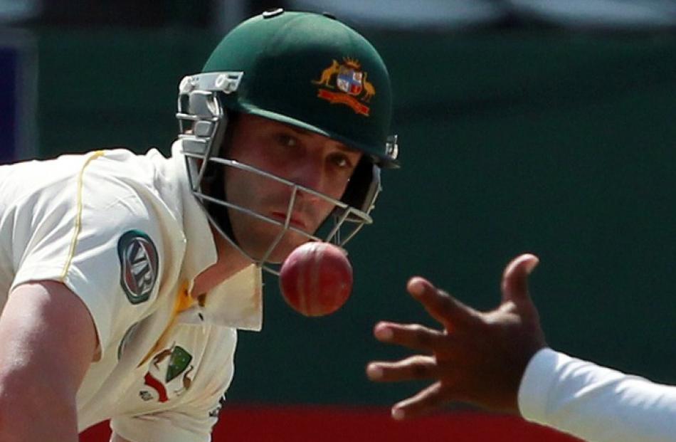 Australian batsman Phillip Hughes watches as Sri Lanka's Lahiru Thirimanne tries to stop the ball...
