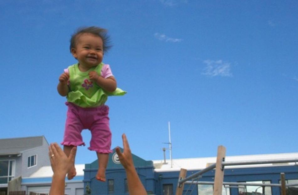 Nine-month-old Maya Rose Satake giggles with glee as she is tossed into the air by her father,...
