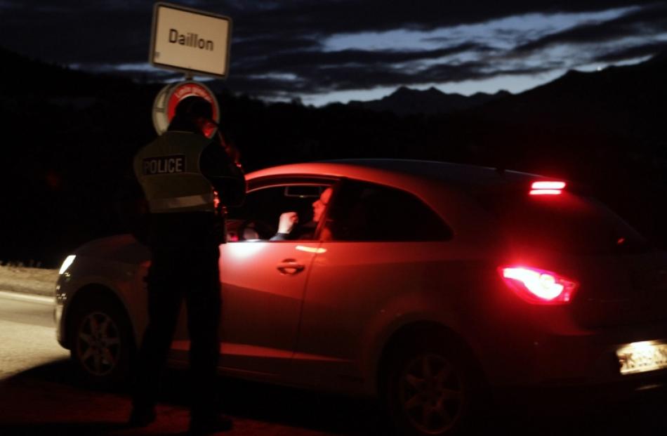 A policeman controls entering traffic at the entrance of the Swiss village of Daillon. Photo by...
