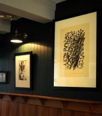 Works by Ralph Hotere hang on the wall of the bar at the Carey's Bay Hotel. Photo by Jane Dawber.