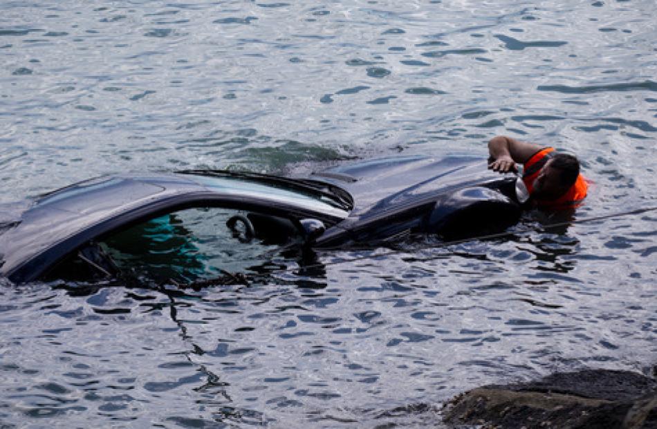 A car is winched out of the water at Northcote Point after a woman lost control and crashed...