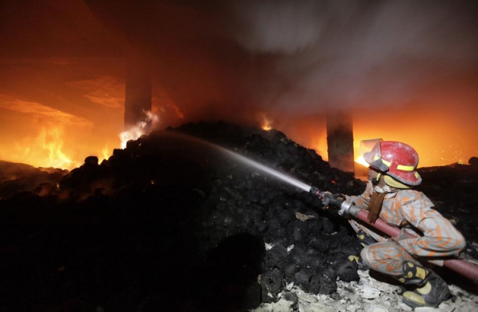 A firefighter tries to control a fire at a garment factory in Savar, outskirts of Dhaka. Photo by...