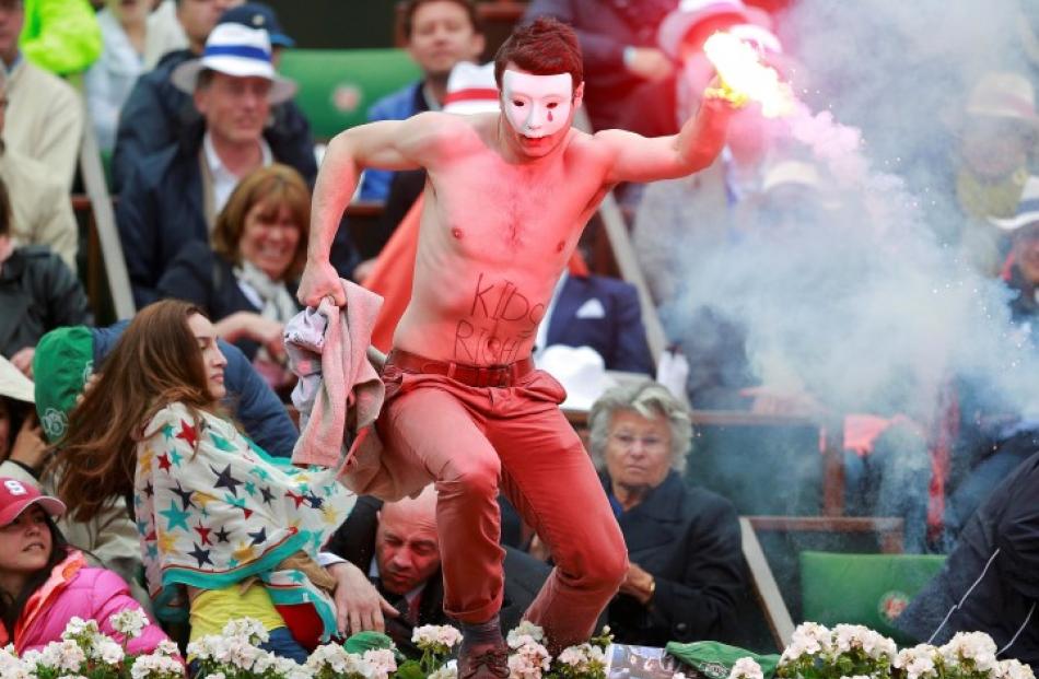 A flare-wielding Homen group protester jumps on to the court during the French Open final between...