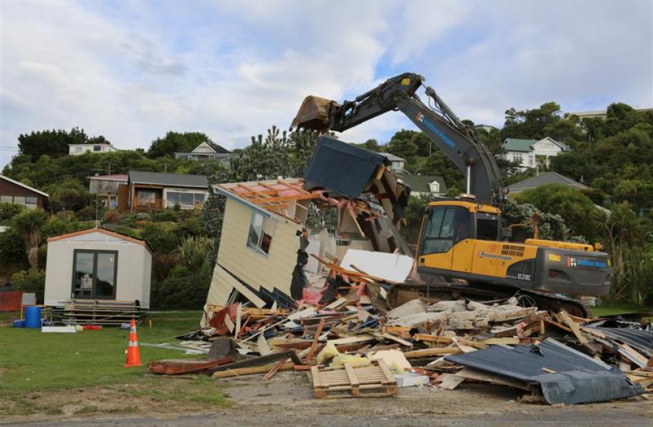 A Fulton Hogan tracked excavator knocks down the old Brighton Surf Life Saving Club building...