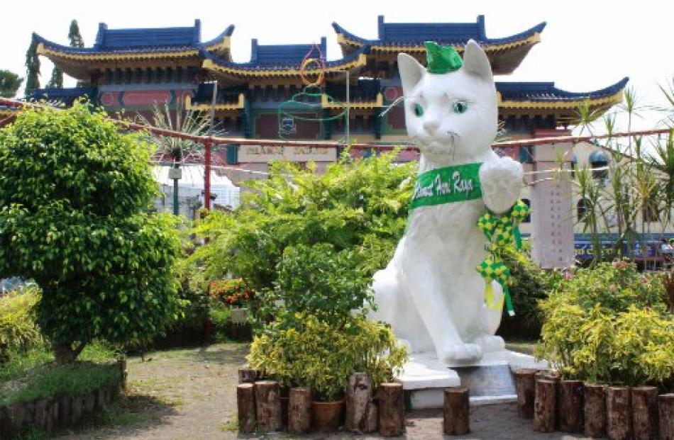 A giant cat statue - sporting a green ribbon to celebrate the end of Ramadan - guards the...