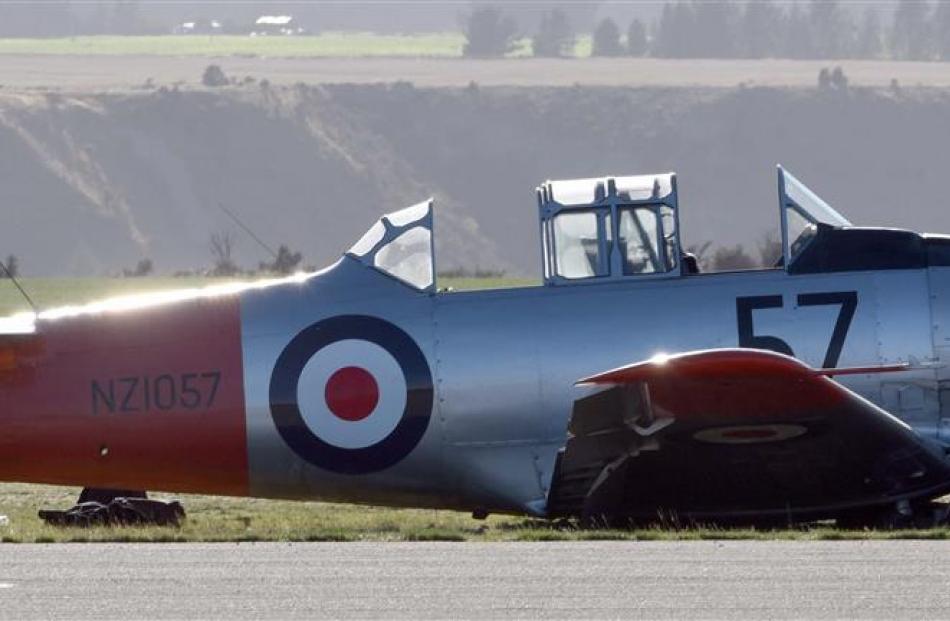 A Harvard with a collapsed undercarriage sits on the edge of the runway at Wanaka Airport...