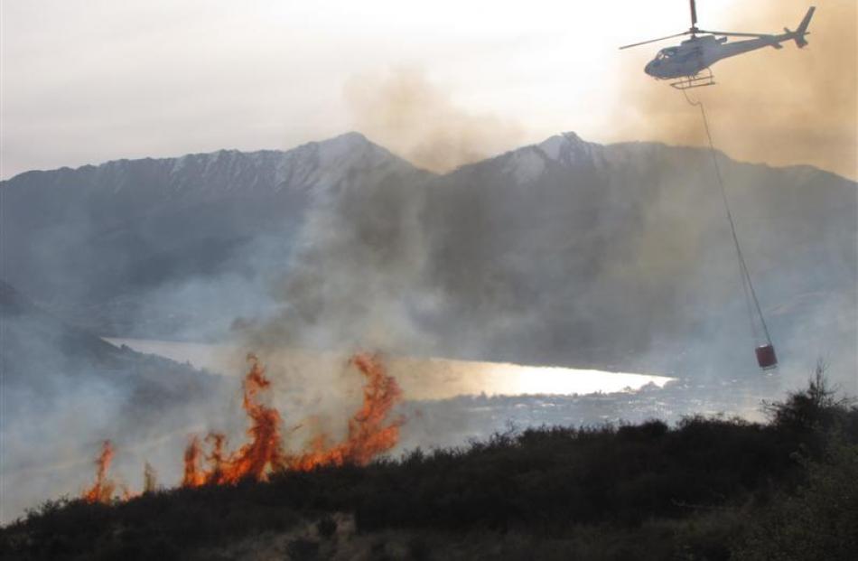 A helicopter attacks an out-of-control burn-off, covering an estimated 40ha, near the Remarkables...