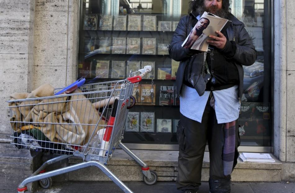 A homeless man reads a magazine outside an international bookstore in central Rome in this...