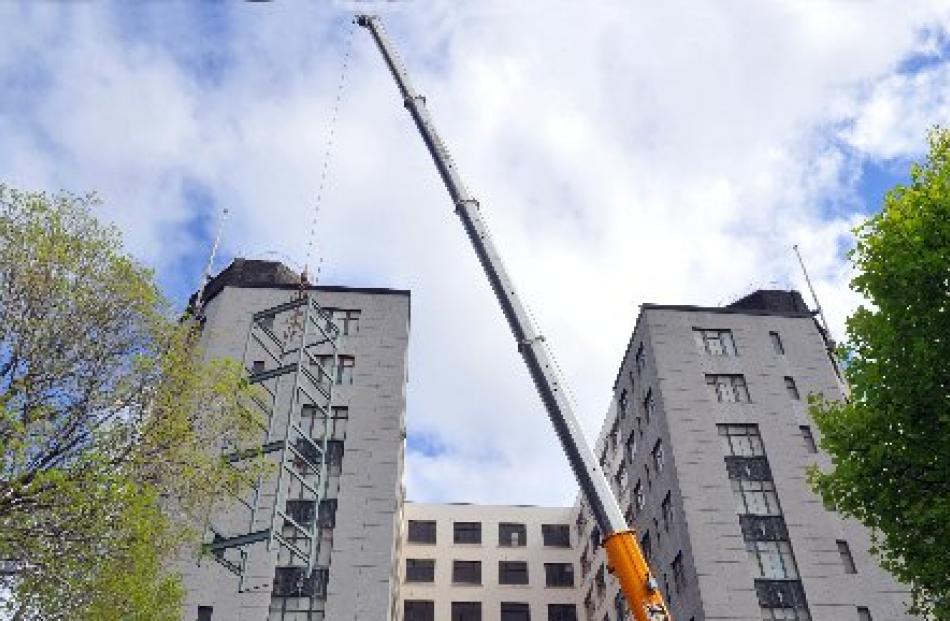 A large crane lifts sections of steel framing through the roof of the former chief post office...