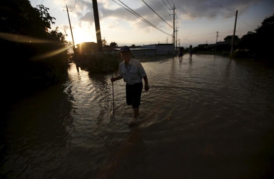 A local resident wades through a residential area flooded by the Kinugawa river, caused by...