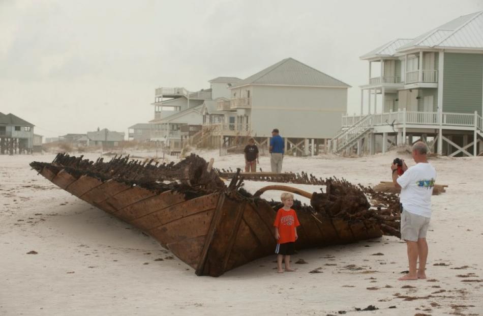 A man takes a photo of his grandson in front of an old ship uncovered as the beach eroded during...