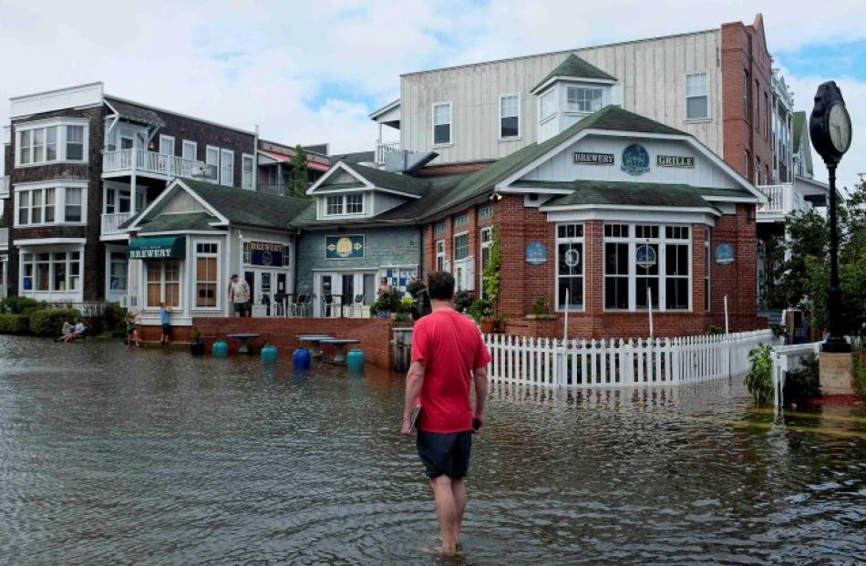 A man walks through a flooded street after Hurricane Arthur passed through in Manteo, North...