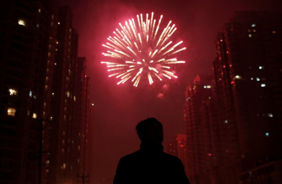 A man watches as fireworks light up the skyline of Shanghai in celebration of Chinese New Year....