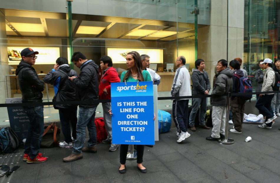 A marketer at work by the queue for the iPhone 5 at the Apple flagship store on George St in...