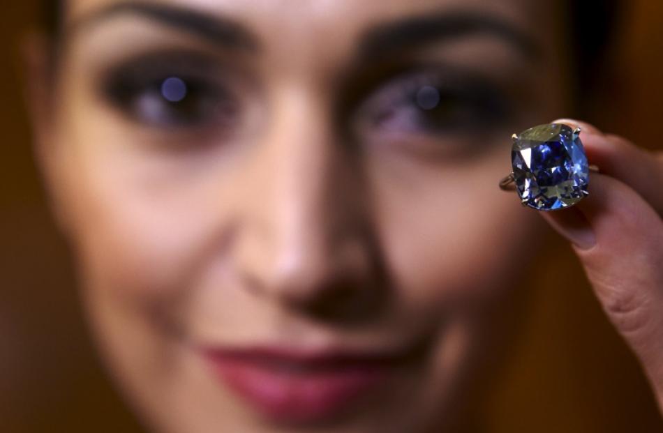 A model poses with a 12.03 carats cushion-shaped fancy vivid blue diamond mounted on a ring at...