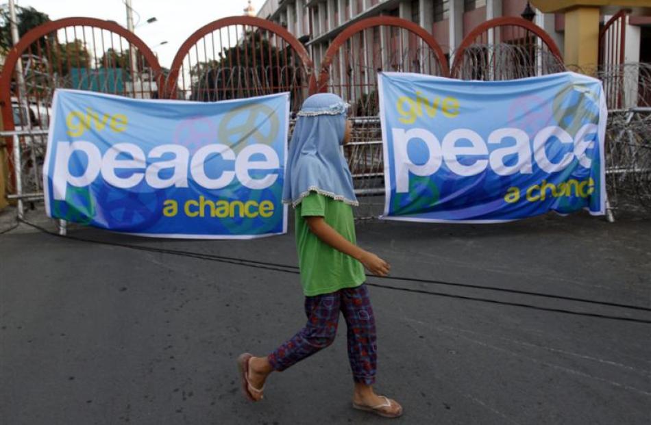 A Muslim girl walks past a banner backing a framework agreement between the Philippines...