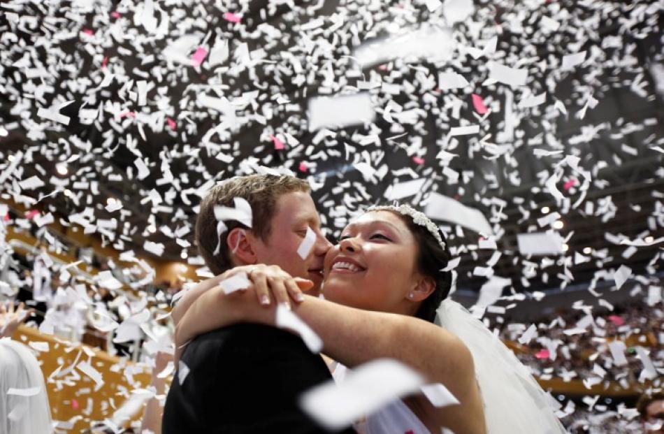 A newlywed couple celebrates during a mass wedding ceremony of the Unification Church at...