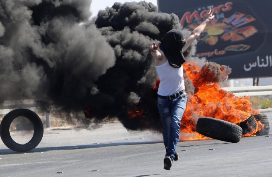 A Palestinian protester gestures to Israeli soldiers during a protest against the Israeli...