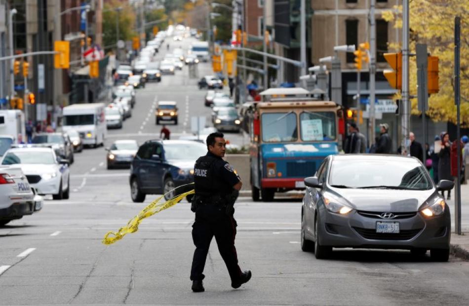 A police officer gathers police tape on Metcalfe Street following the shootings in downtown...