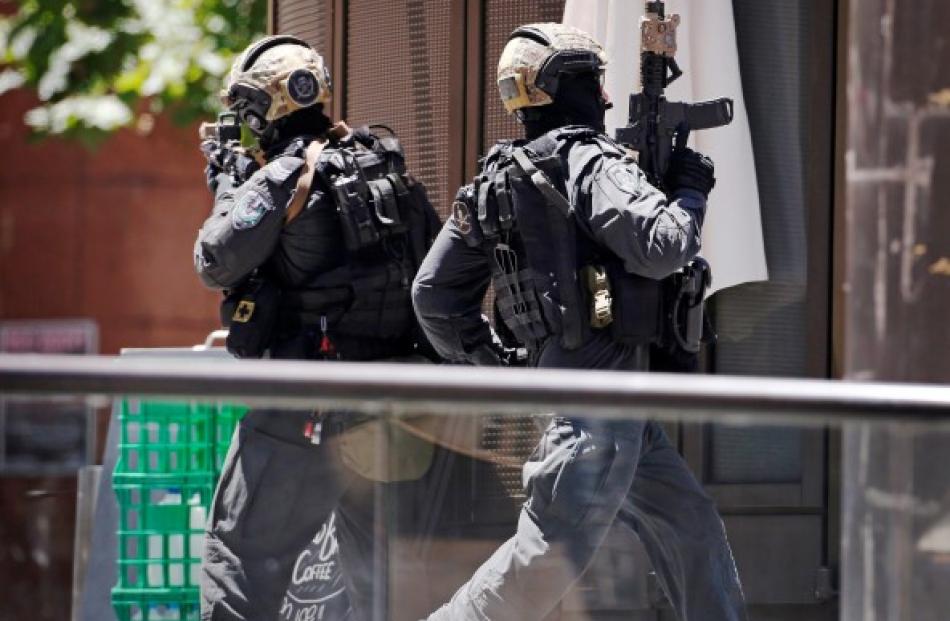 A police officer runs across Martin Place near Lindt cafe, where hostages are being held, in...