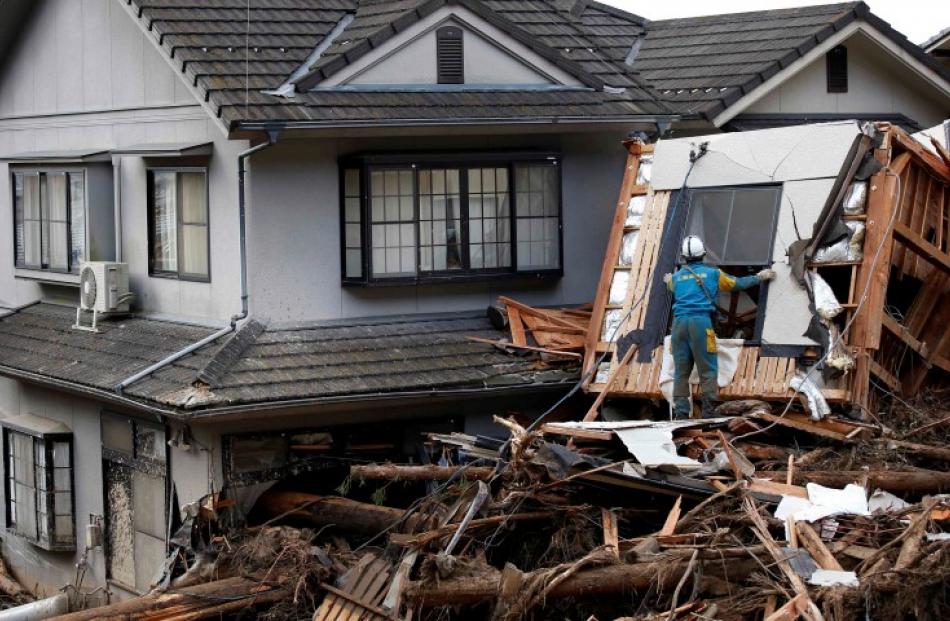 A police officer searches for survivors at a site where a landslide swept through a residential...