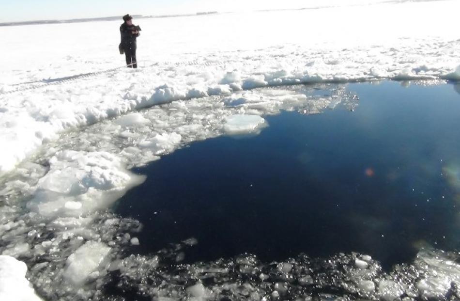 A policeman works near an ice hole, said to be the point of impact of a meteor seen earlier in...