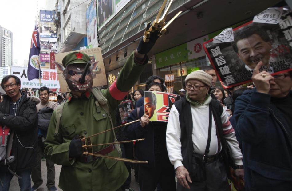 A protester dressed as a cultural revolution red guard wearing a wolf mask gestures during a...