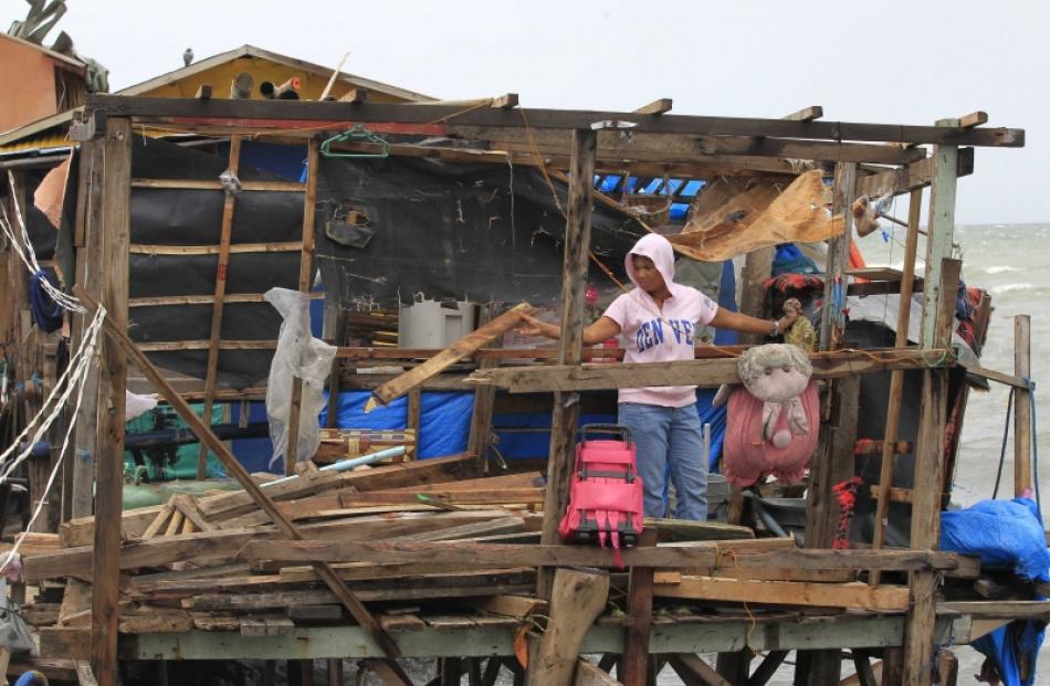 A resident salvages her belongings inside a damaged house after strong winds brought by Typhoon...