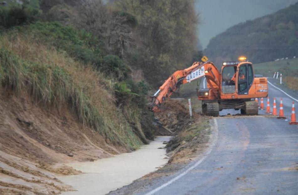 A roading crew works yesterday morning to repair damage to the Southern Scenic Route, reducing...