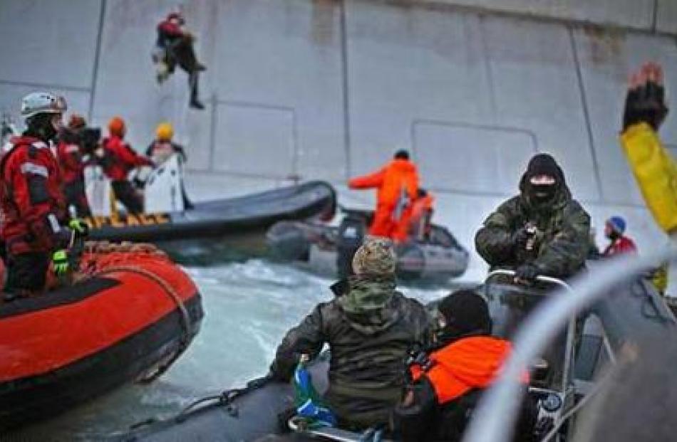 A Russian Coast guard officer is seen pointing a gun at a Greenpeace International activist as...