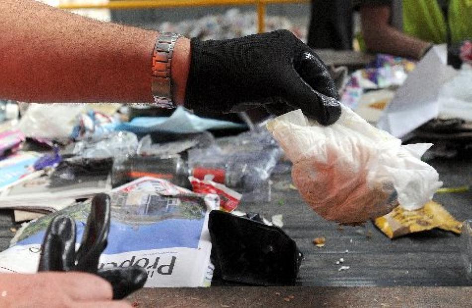 A used disposable nappy is plucked from the recycling sorting line.