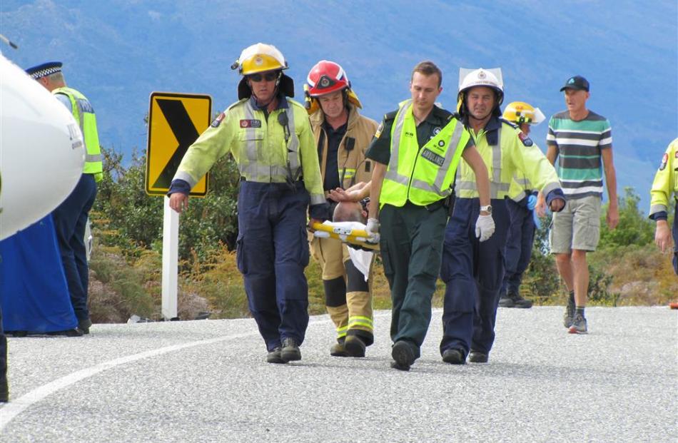 A West Coast motorcylist injured in a collision near Lake Hawea yesterday is carried to a waiting...