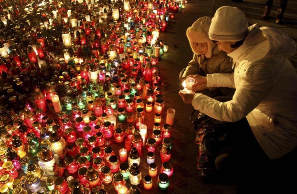 A woman and child light a candle to pay respects to fallen anti-Yanukovich protesters in the...