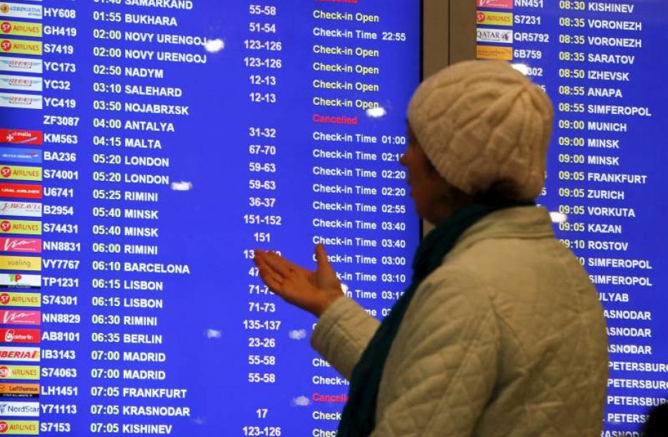 A woman gestures while standing near an information board, at Domodedovo airport outside Moscow,...