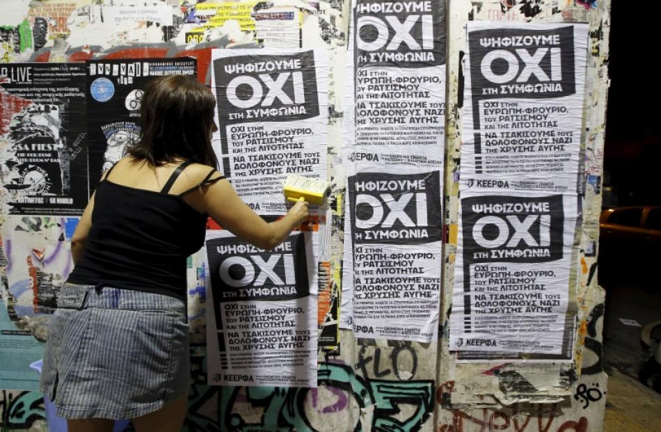 A woman puts up referendum campaign posters with the word "No" in Greek in Athens, Greece. Photo...