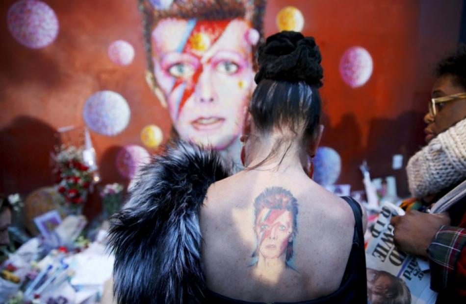 A woman with a David Bowie tattoo visits a mural of the singer in Brixton, south London. REUTERS...