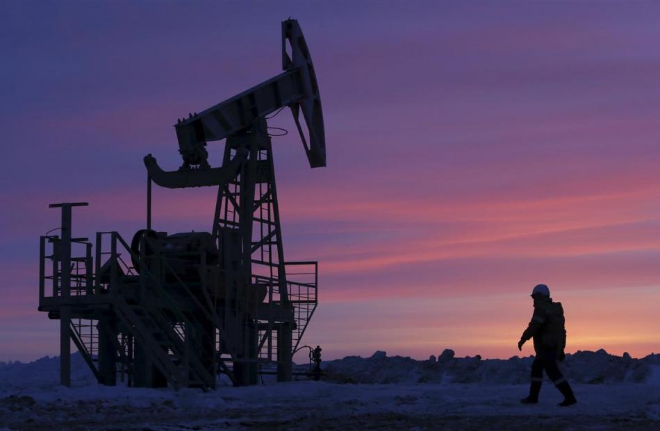A worker walks past a pump jack on an oil field  near the village of Nikolo-Berezovka, northwest...