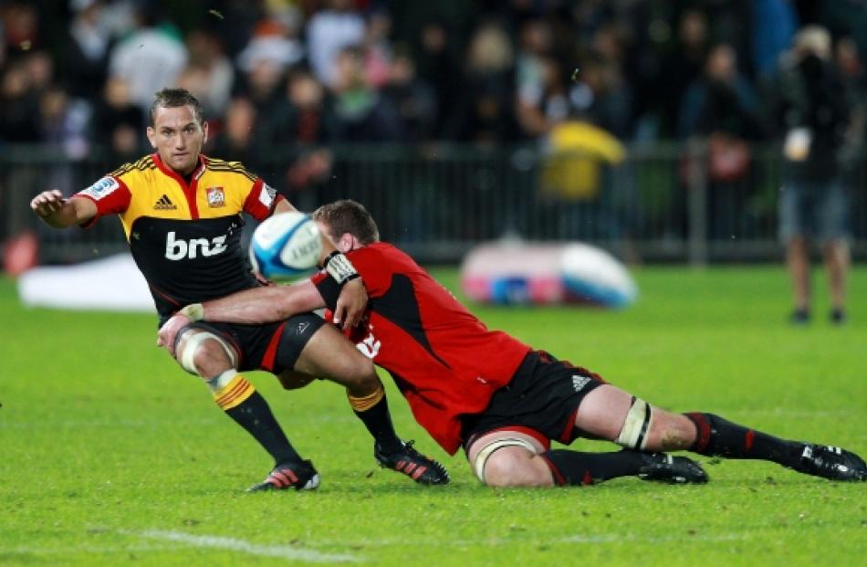 Aaron Cruden of the Chiefs gets a kick away while being tackled during the round three Super...