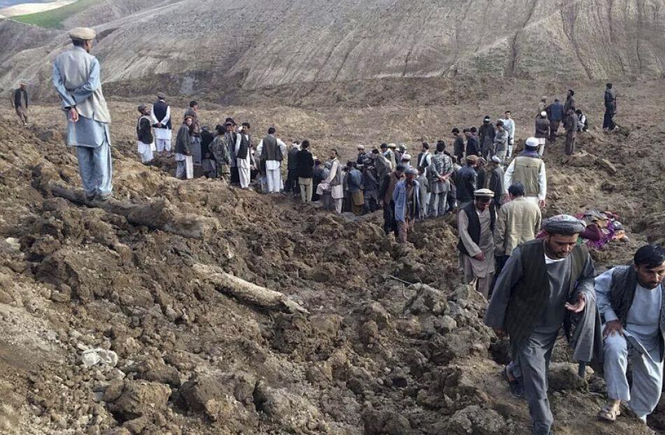 Afghan villagers gather at the site of a landslide at the Argo district in Badakhshan province....
