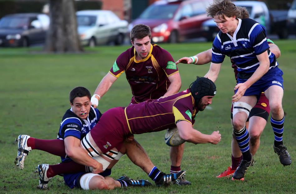 Alhambra Union No 8 Graeme Cashmore is tackled by Kaikorai flanker Lee Allan as players from each...