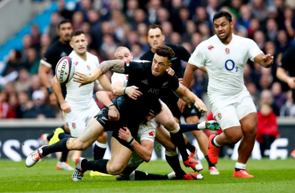 All Black second five Sonny Bill Williams offloads the ball as he is caught by the England...