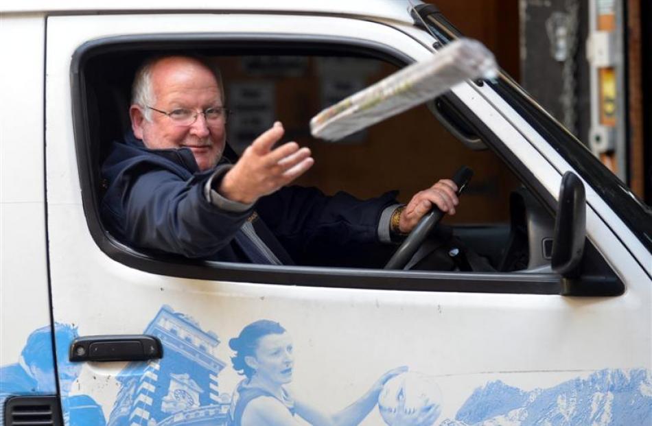 Allied Press distribution manager Warren Godfrey tosses a newspaper from a delivery van for the...