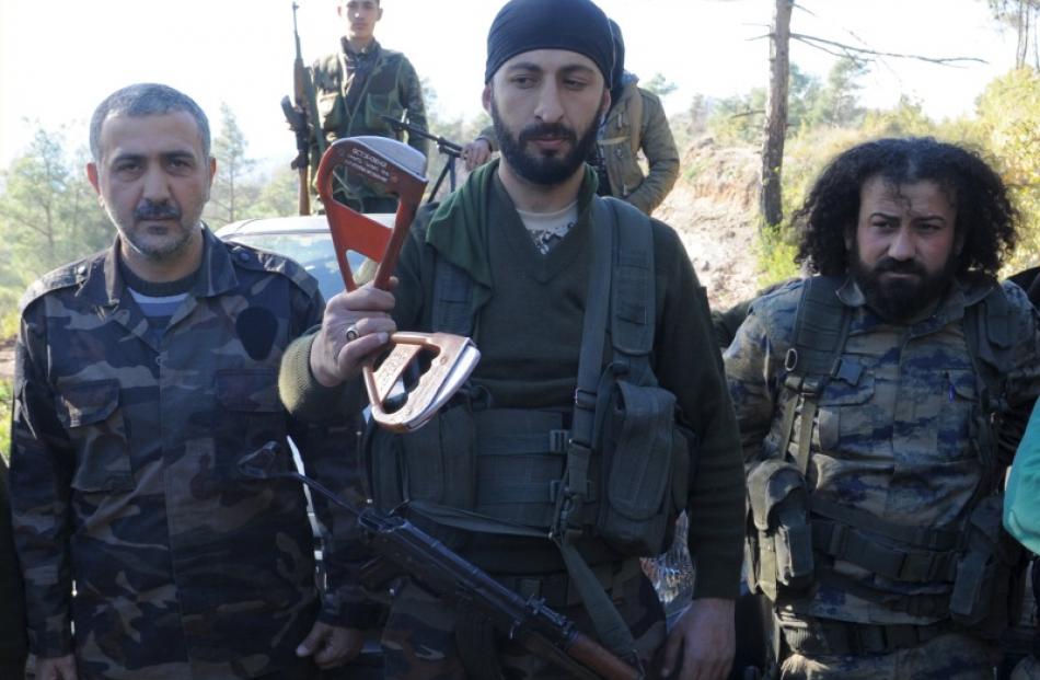 Alpaslan Celik (centre), a deputy commander in a Syrian Turkmen brigade, holds handles believed...