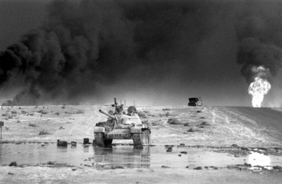 An abandoned Iraqi tank in front of burning oil wells south of Kuwait City, Iraq, in 1991. Photo...